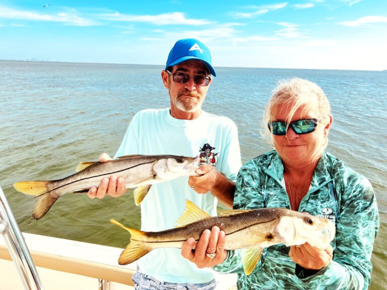 A couple holding a snook aboard the boat