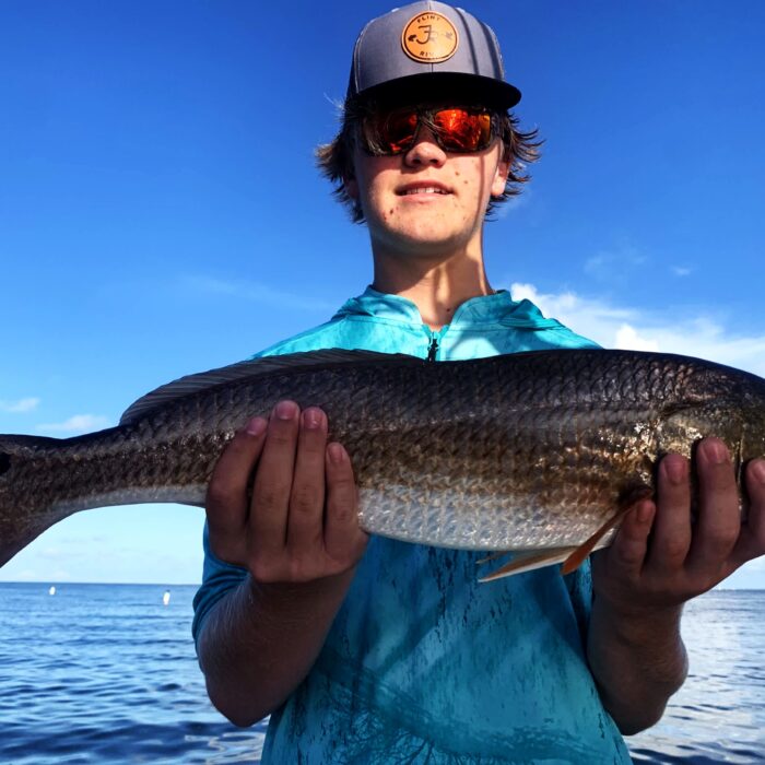 A young angler holding a bull redfish