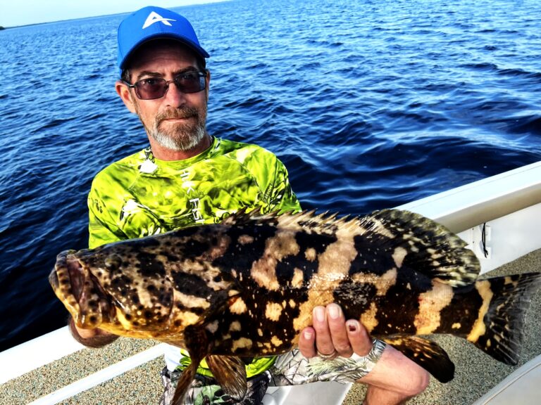 Angler holding a goliath grouper aboard the boat