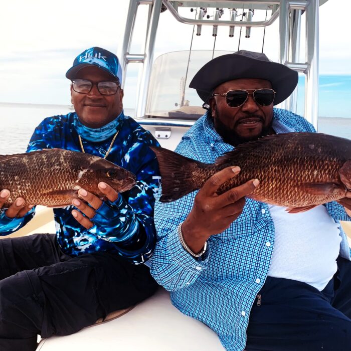 Two anglers holding mangrove snapper