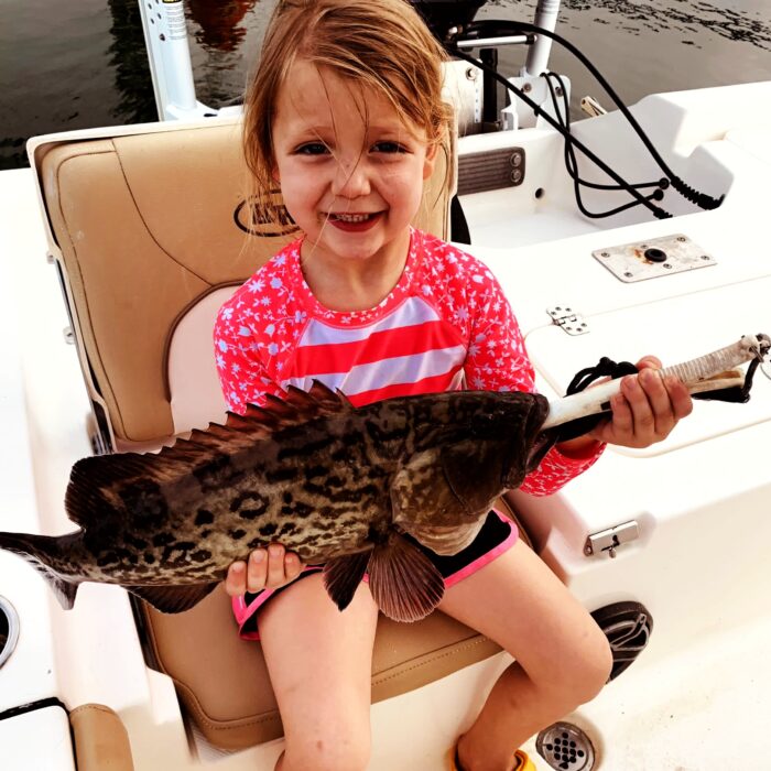 A young girl holding a grouper