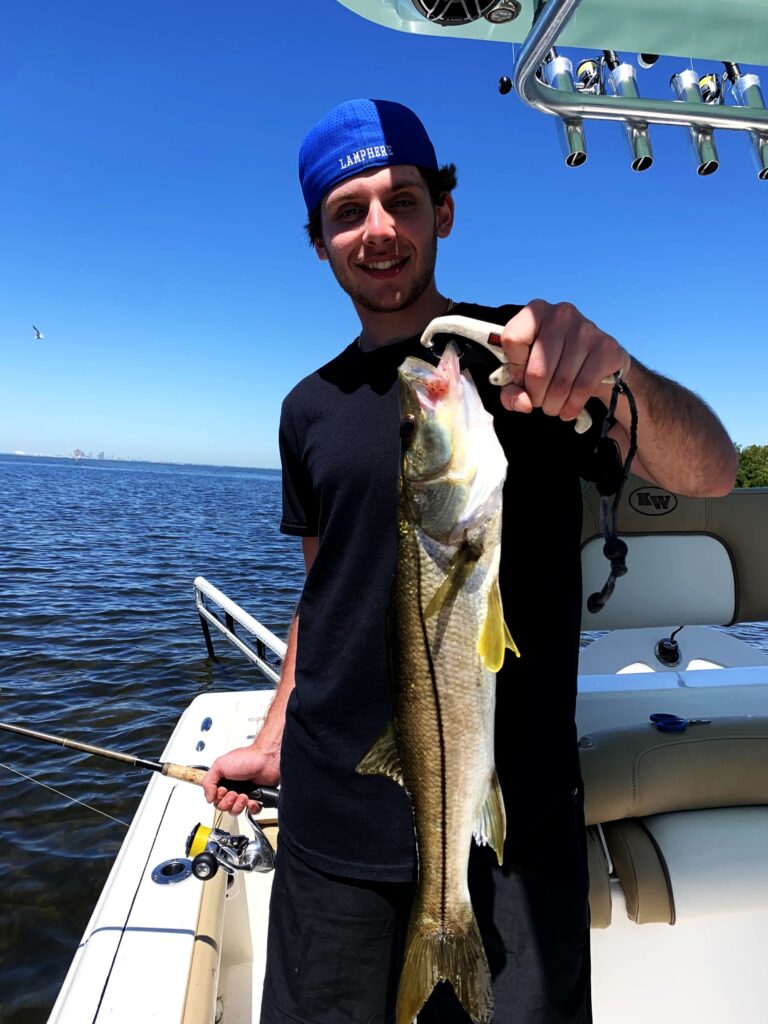 Angler holding a snook alongside the boat