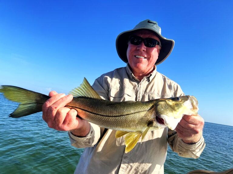 Angler holding a snook against a clear blue sky